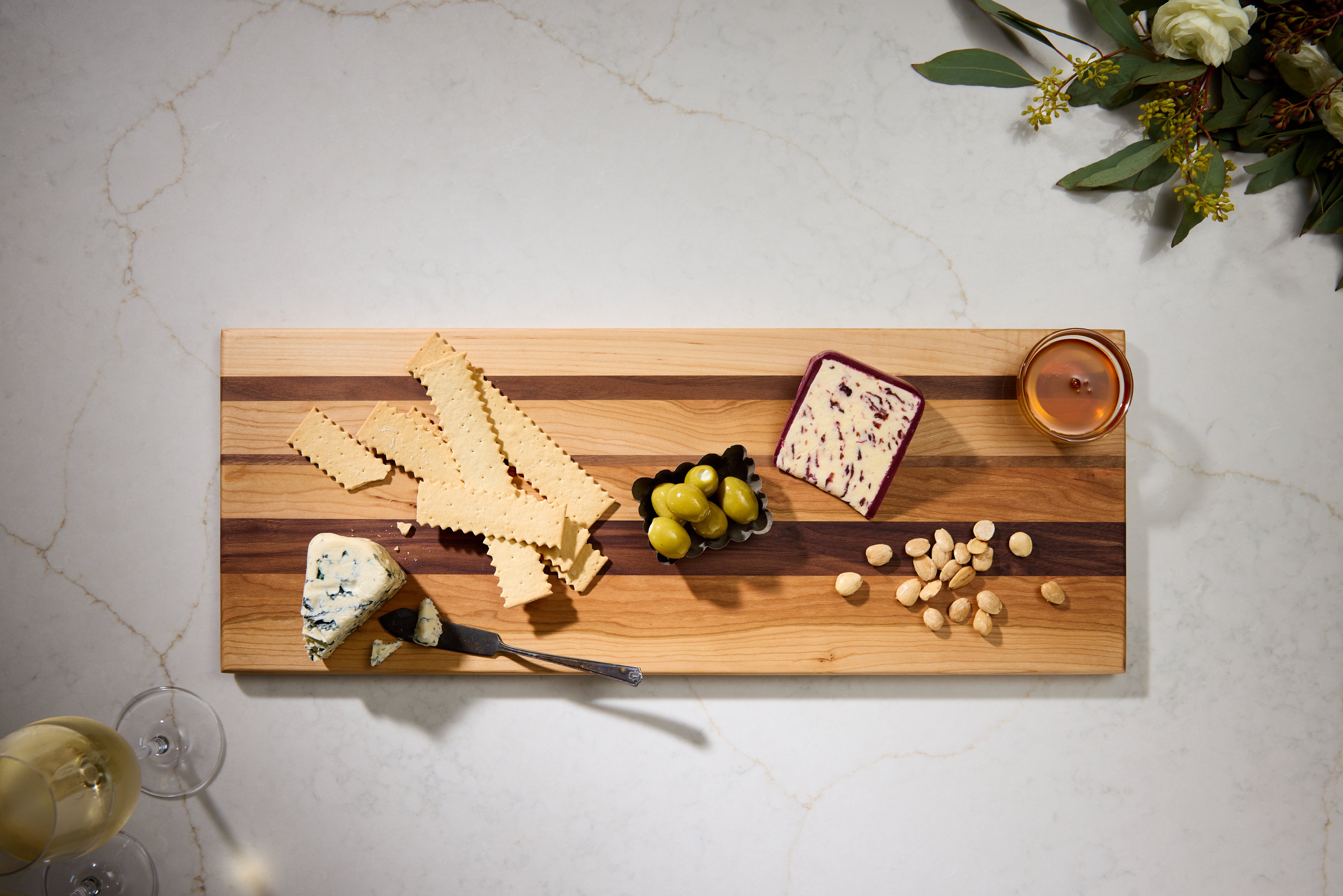 Charcuterie cutting board featuring cheese, olives, and crackers, styled for entertaining or wood decor display.