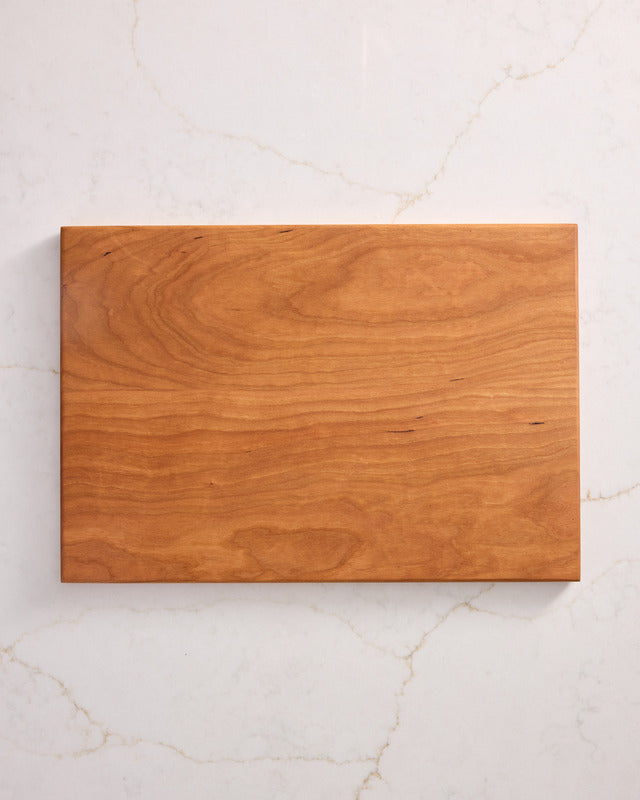 Medium cherry wood cutting board with warm tone and polished surface, best chopping board made from healthiest cutting board material.