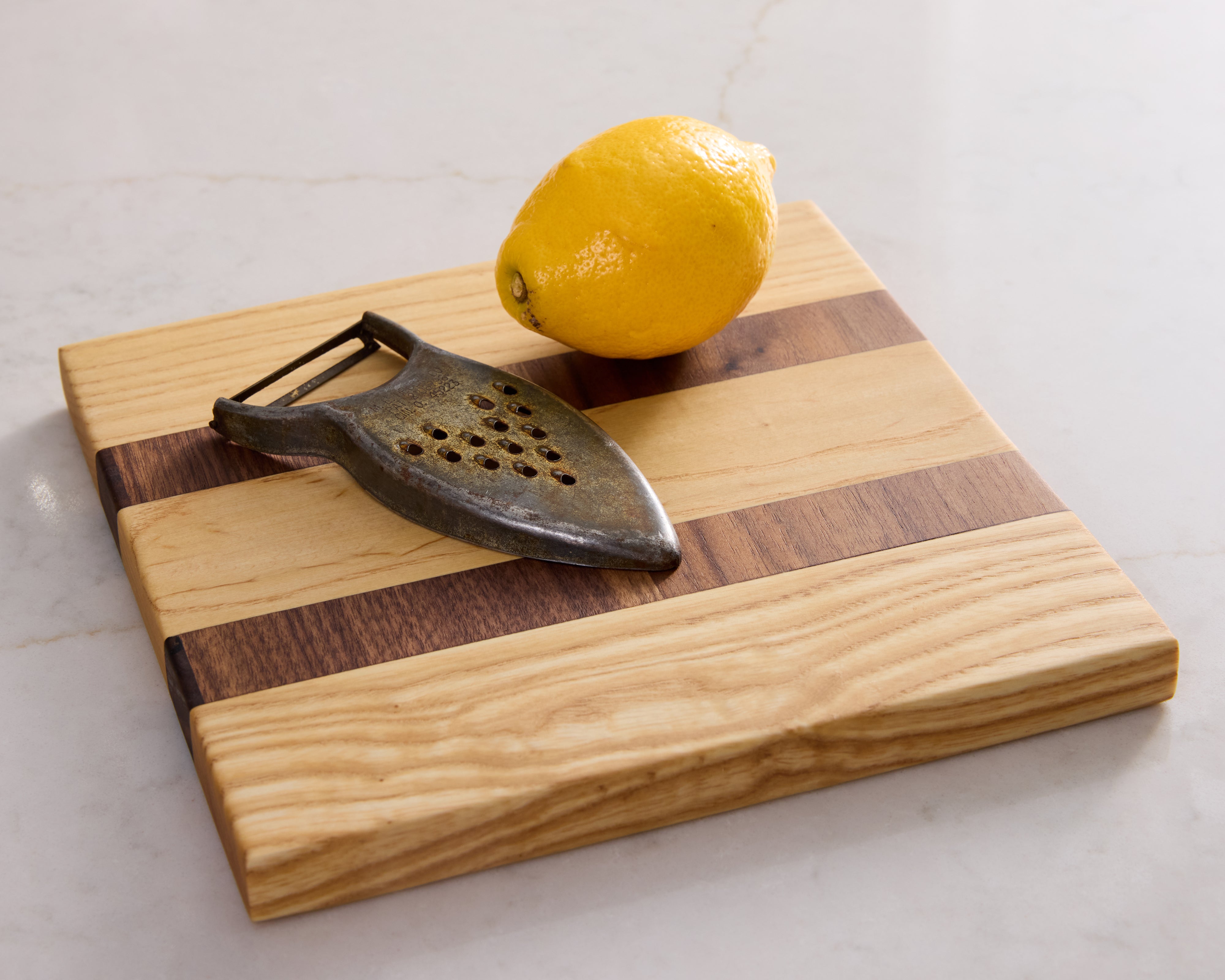 Non-toxic maple and walnut prep board styled with lemon and peeler — a healthy and elegant kitchen or bar essential.