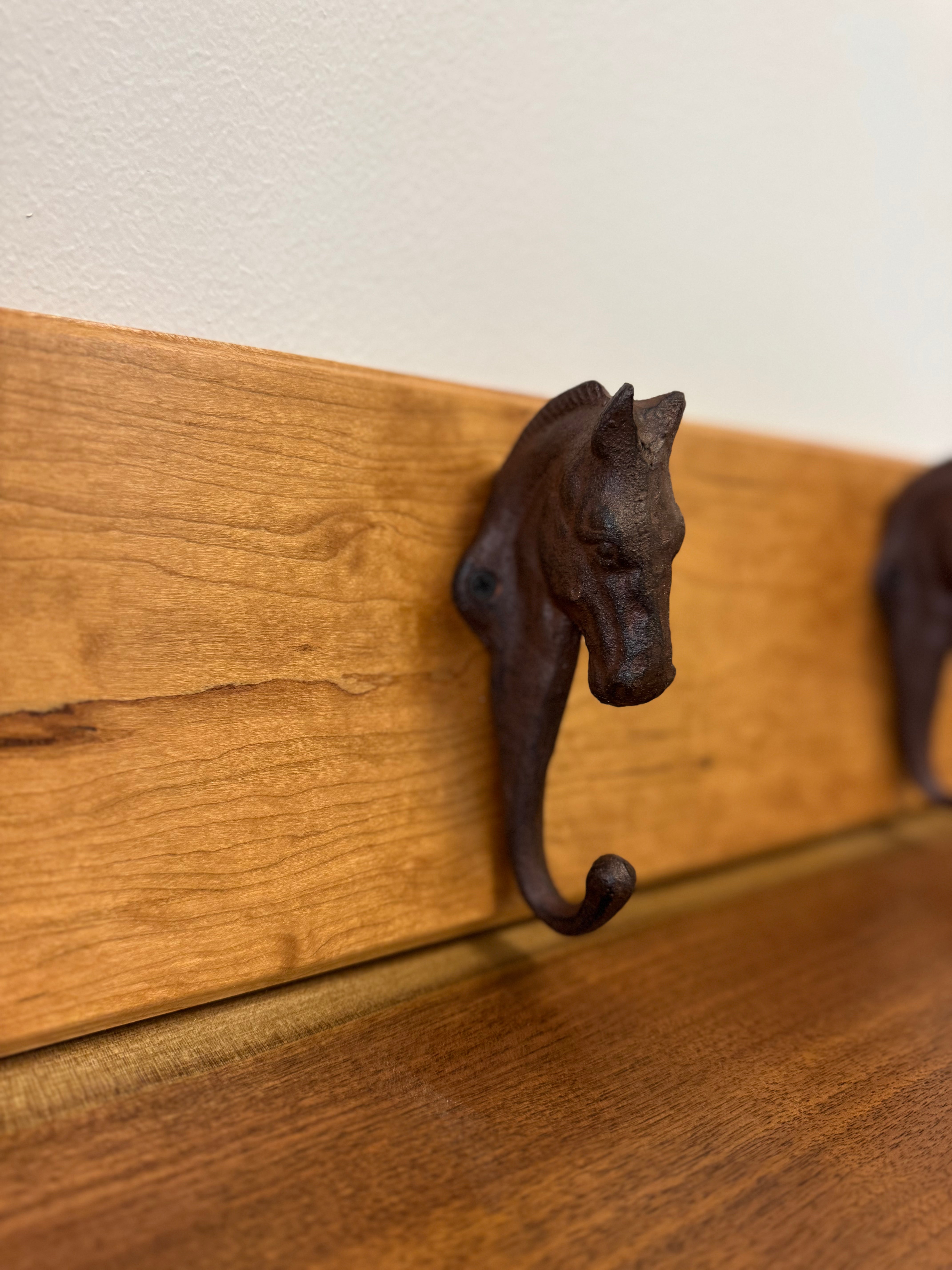 Rustic cast iron horse-head hook mounted on a natural wood board, a stylish accent for farmhouse or western-inspired decor.