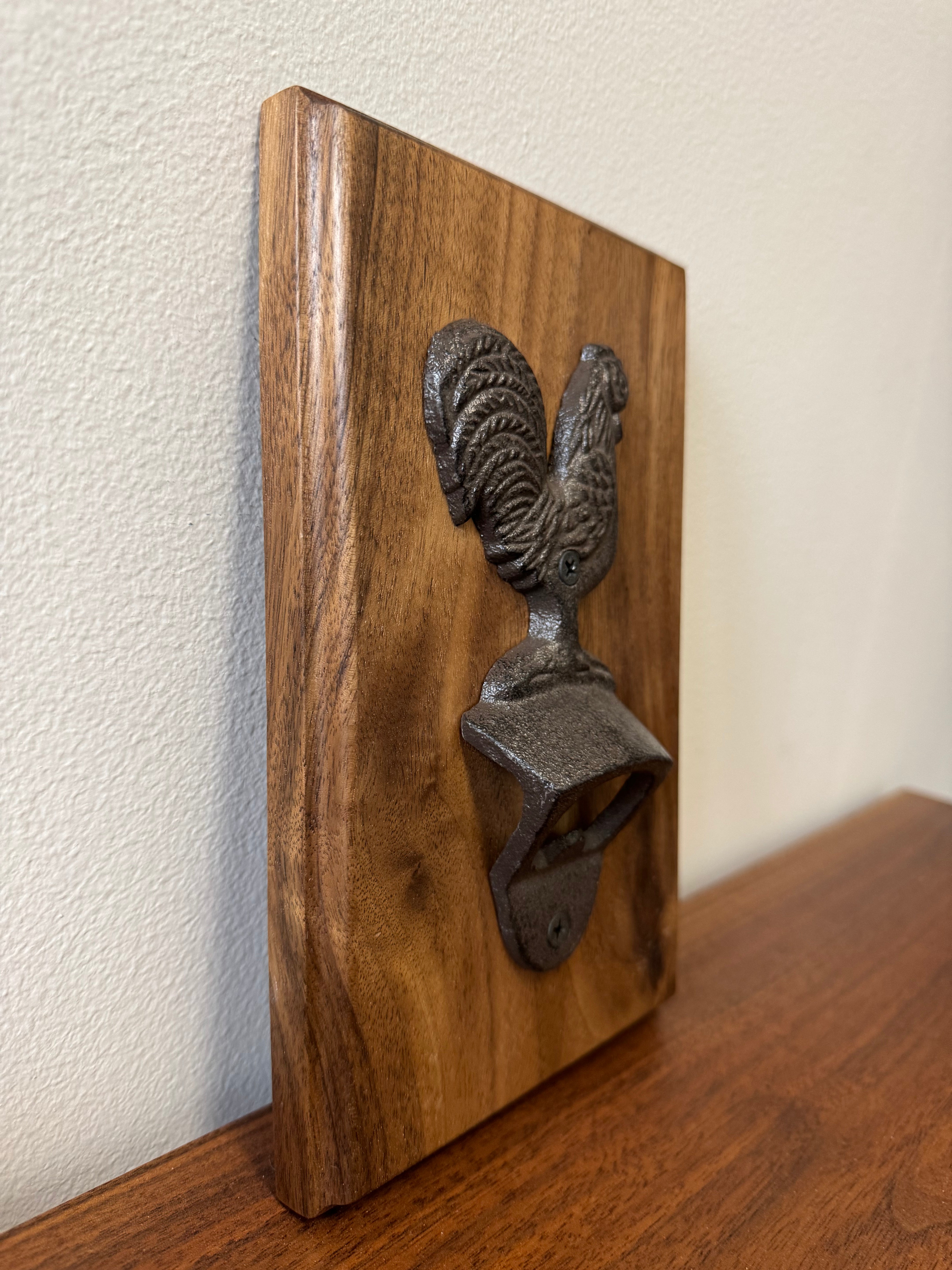 Handcrafted walnut wood wall-mounted bottle opener with a cast iron rooster design, highlight its rustic textured finish.