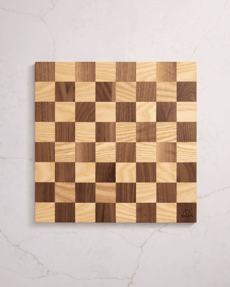 Custom maple and walnut chess board seen from the top, resting on white marble — a unique handmade board for home decor.