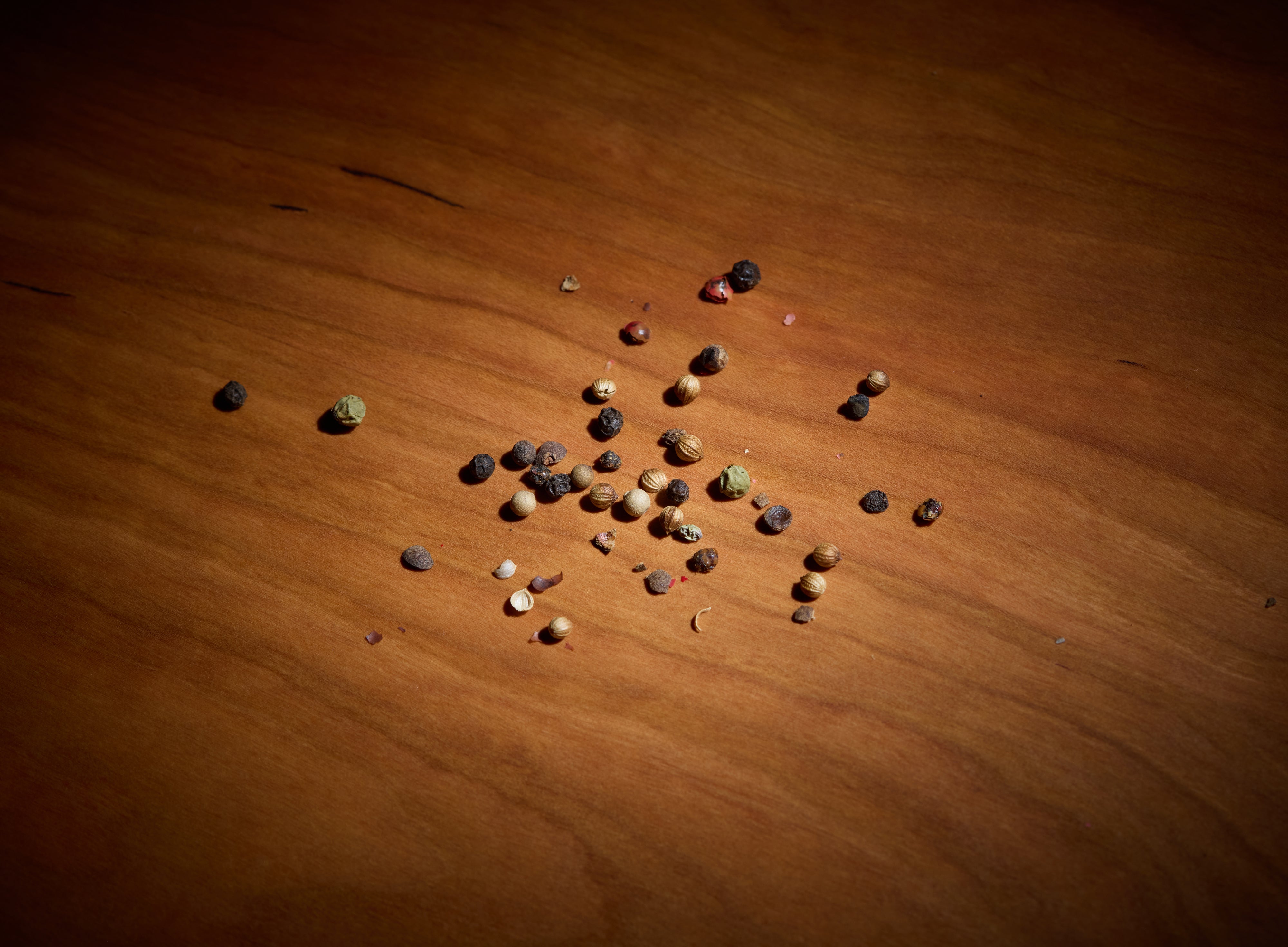 Close-up of walnut cutting board with peppercorns, showing is walnut wood food safe and a non toxic cutting board for prep