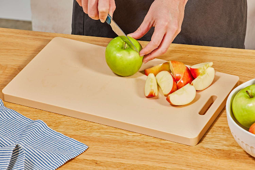 Chopping apples on a plastic cutting board raises questions about safest cutting board material for daily food prep.