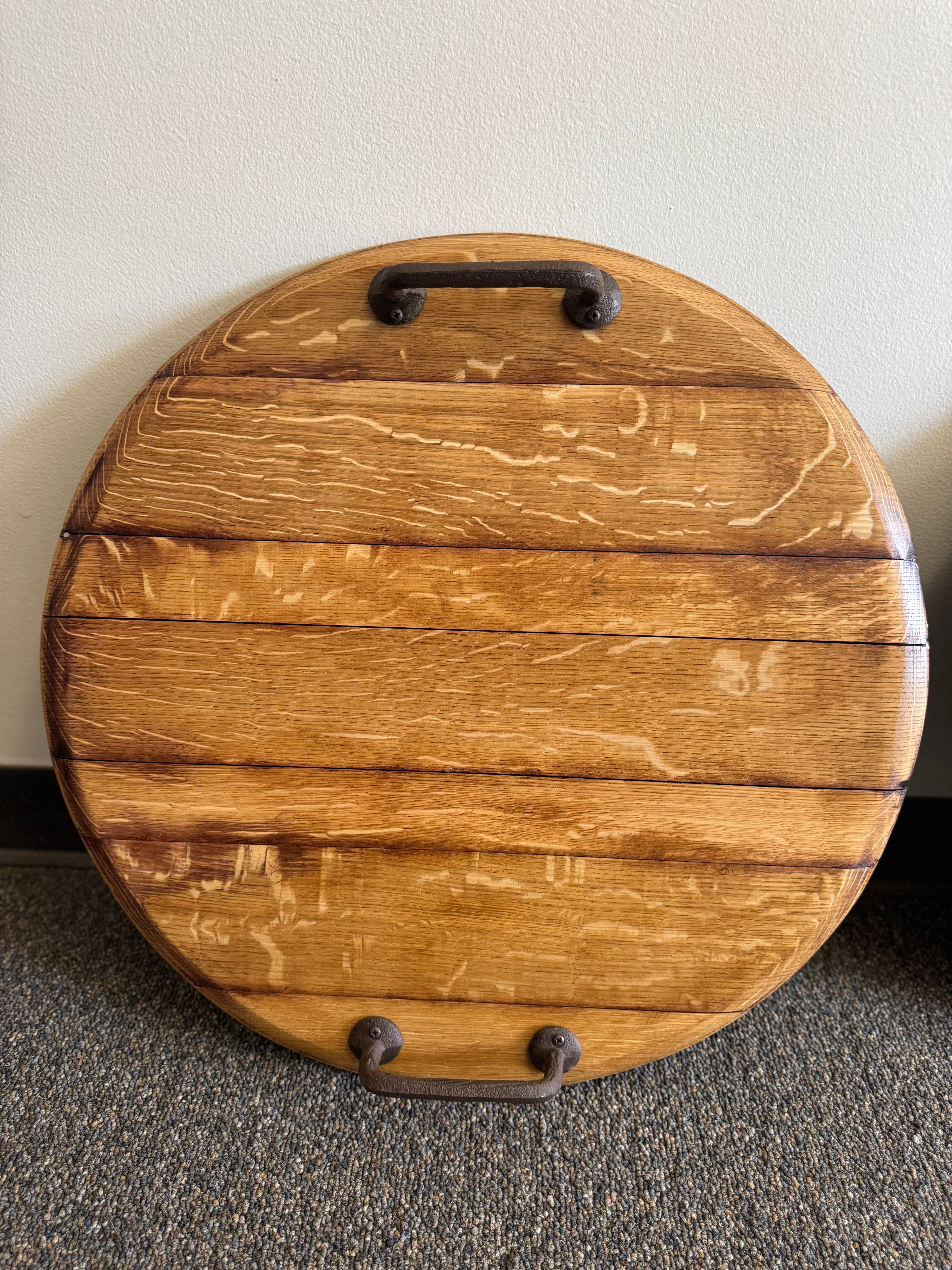 Handcrafted round wooden serving tray with sturdy metal handles, perfect as a cheese tray or rustic charcuterie board.